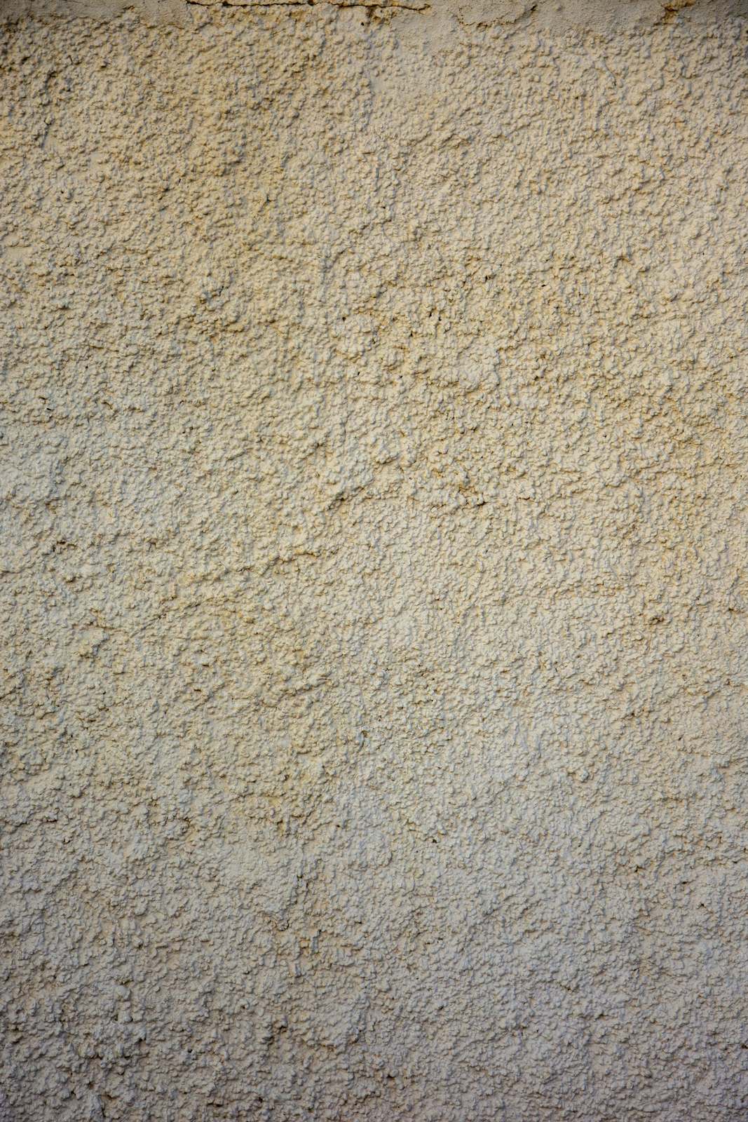 Close-up van een grove, lichtbeige pleisterstructuur